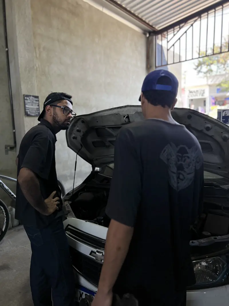 Mecânicos conversando ao lado de um carro com o capô aberto